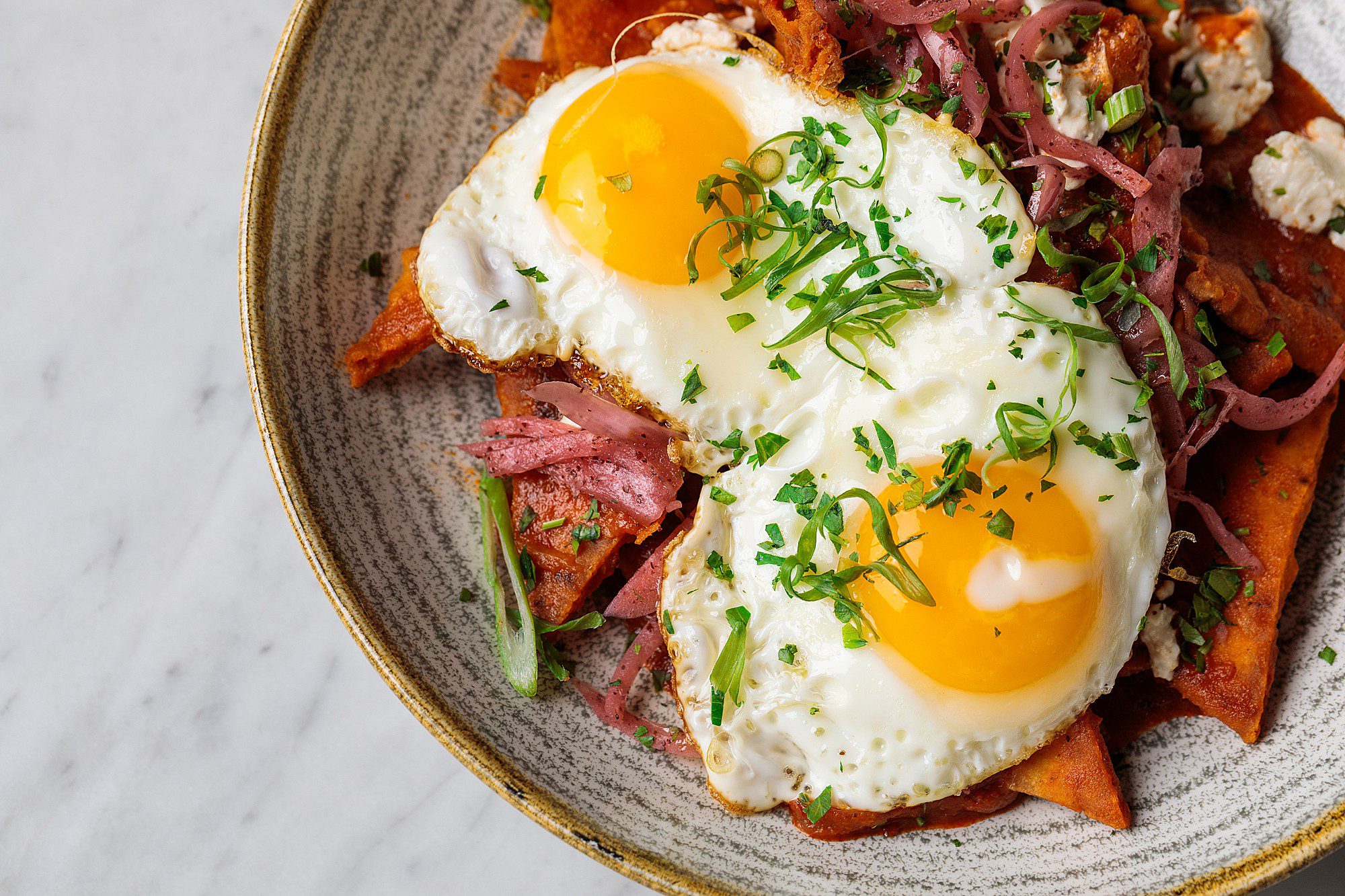 eggs over pitaquiles in a ceramic custom bowl