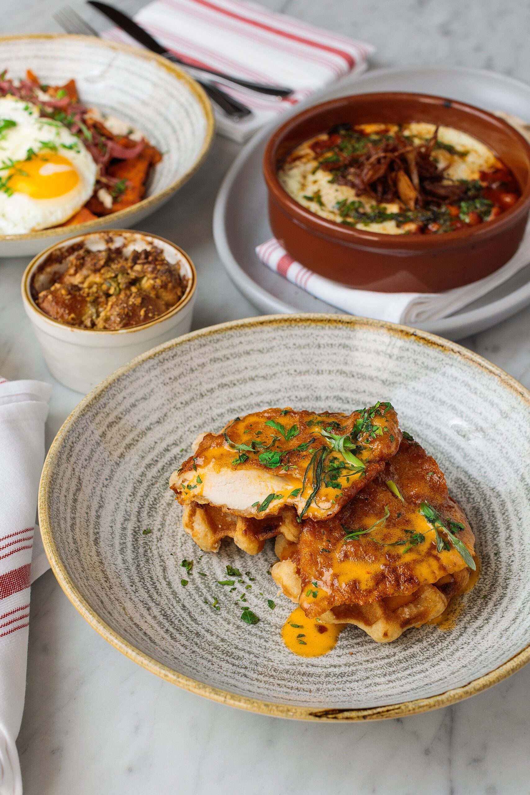 chicken and waffles brunch dish with other brunch plates in the background