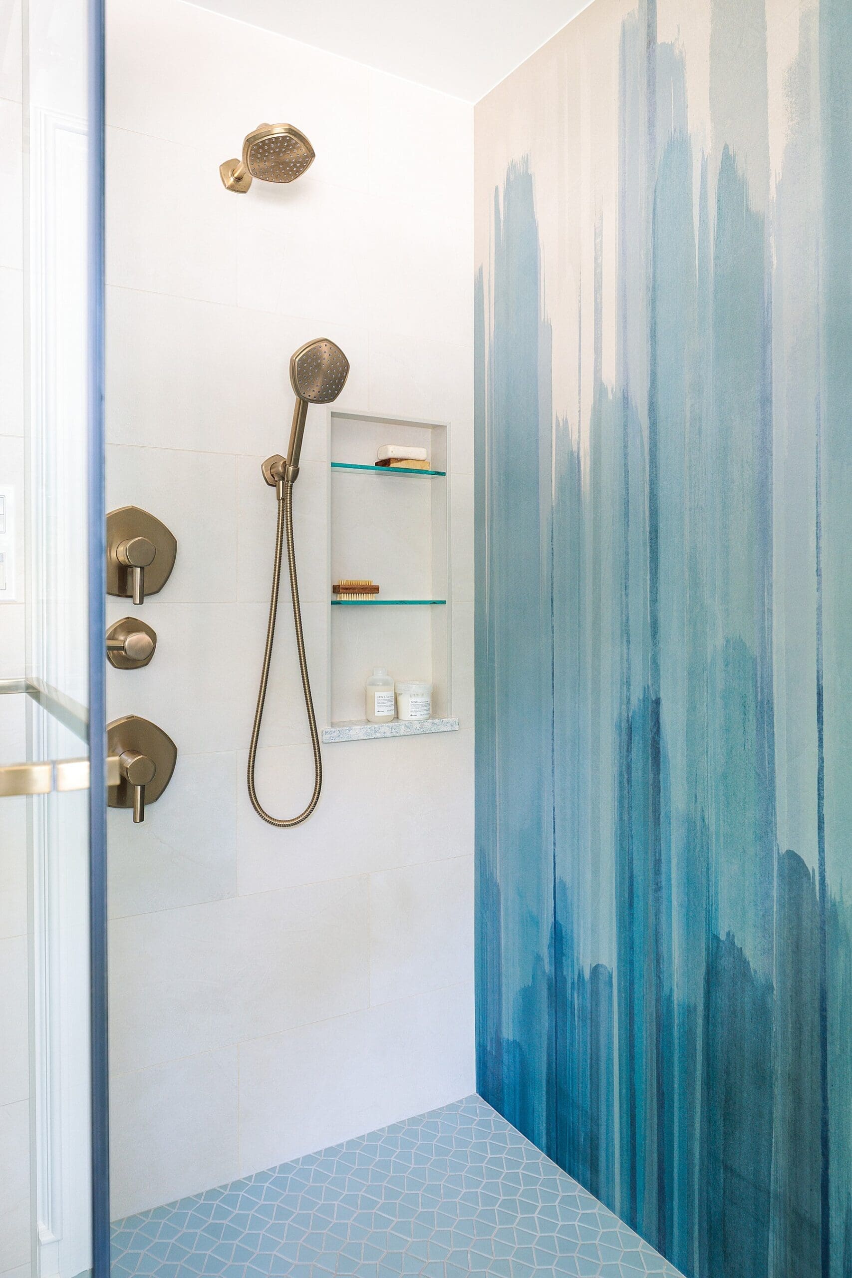 modern shower with brass hardware and a blue watercolor wall tile